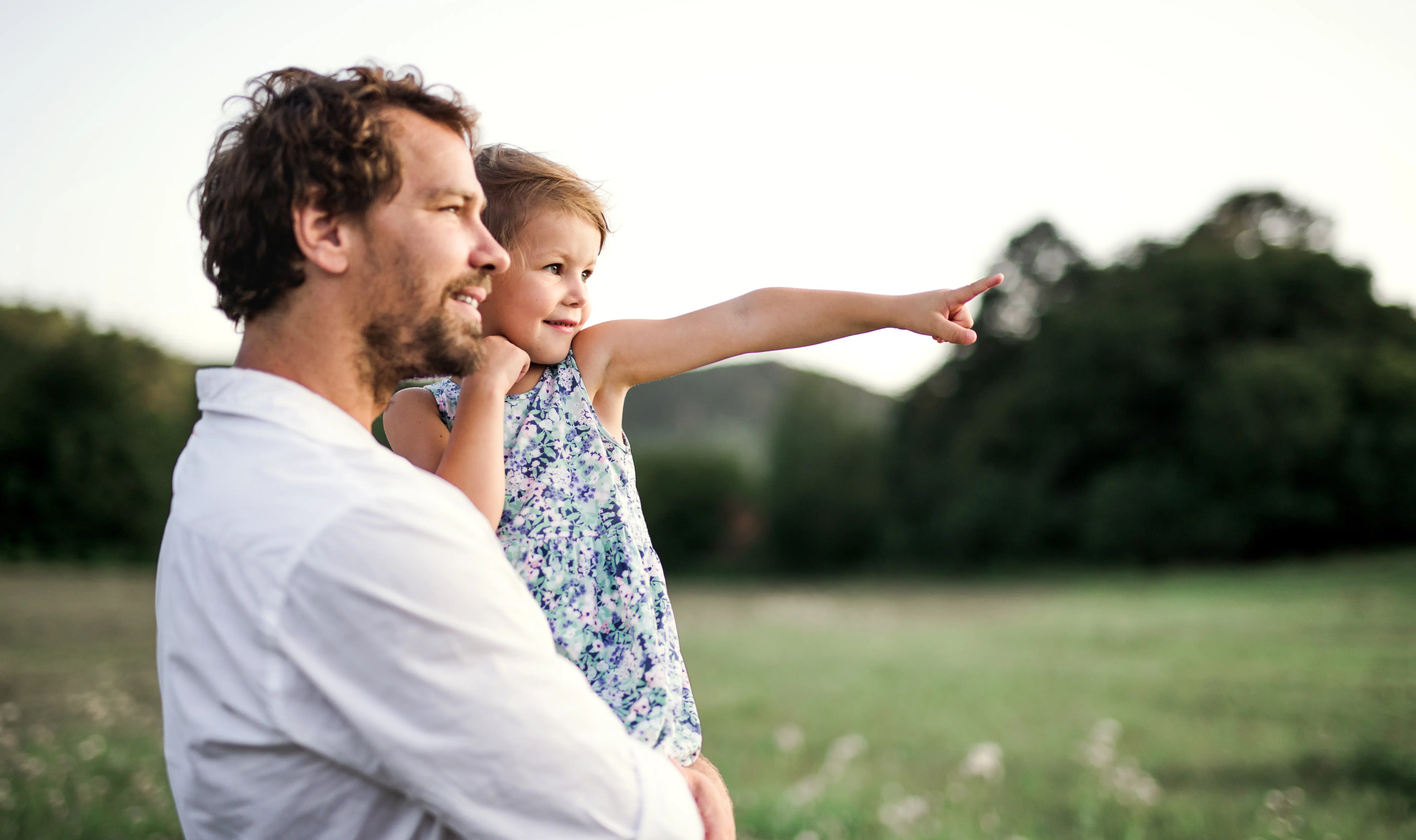 Young father in nature holding small daughter in the arms. Copy space. mision